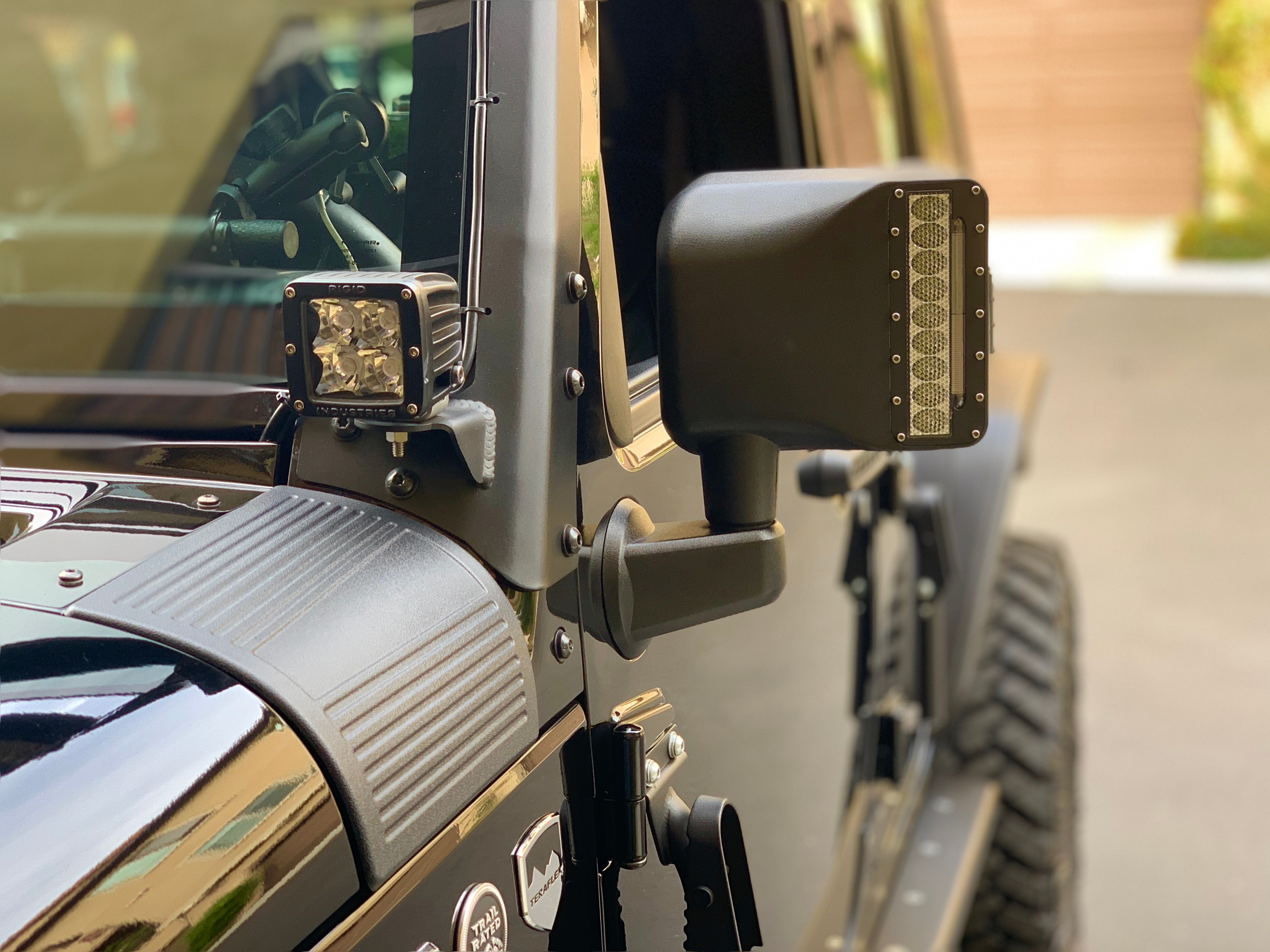 Jeep Wrangler JK with aftermarket A-pillar LED pod lights and LED side mirror lights installed for improved auxiliary lighting and trail visibility.