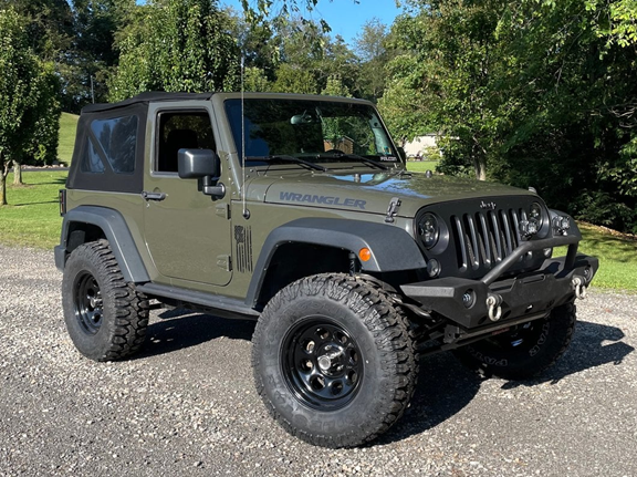 Green Jeep Wrangler with aftermarket lift kit showing increased ride height