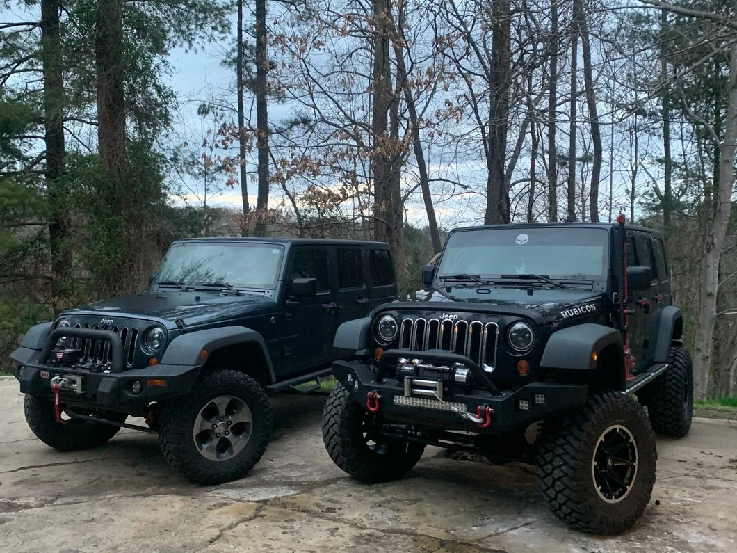 Two Jeep Wrangler JK Unlimited models parked side by side, comparing a stock-height suspension with a lifted off-road suspension setup.