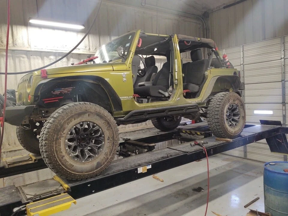 Lifted Jeep Wrangler JK on a wheel alignment rack after a suspension upgrade, preparing to adjust caster, toe, and steering geometry.