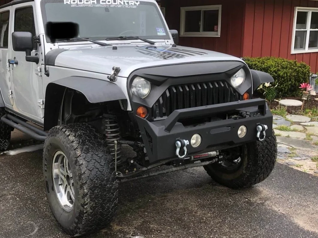 Silver Jeep Wrangler JK Unlimited with a suspension lift, aftermarket front bumper, and oversized all-terrain tires, illustrating increased ride height and suspension geometry.