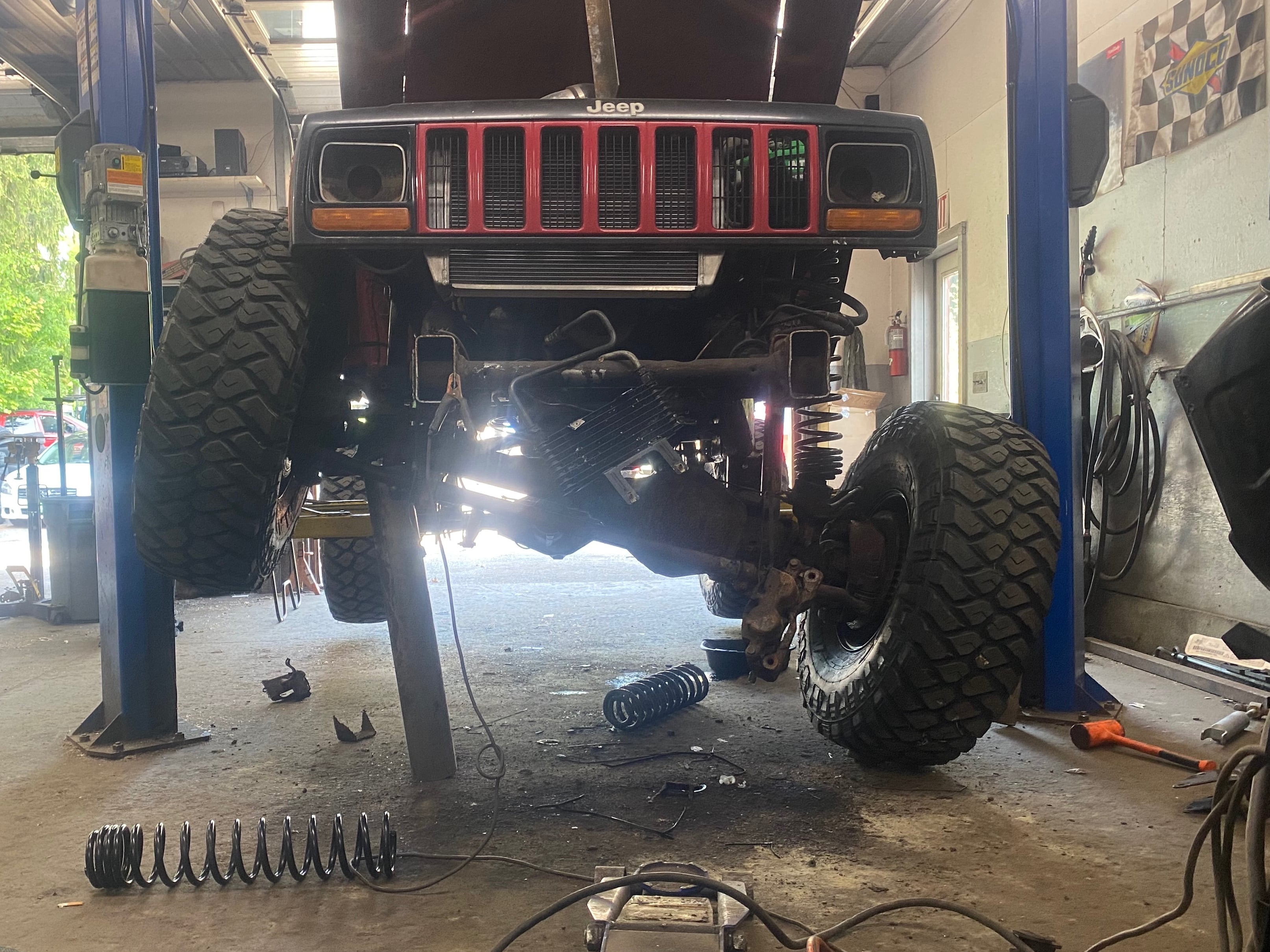 Jeep Cherokee XJ on a lift with the front suspension removed during a solid axle or suspension rebuild.